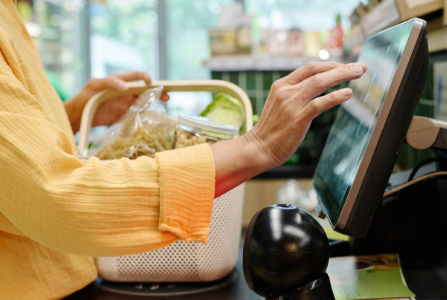 Customer using a touchscreen checkout at a retail counter.