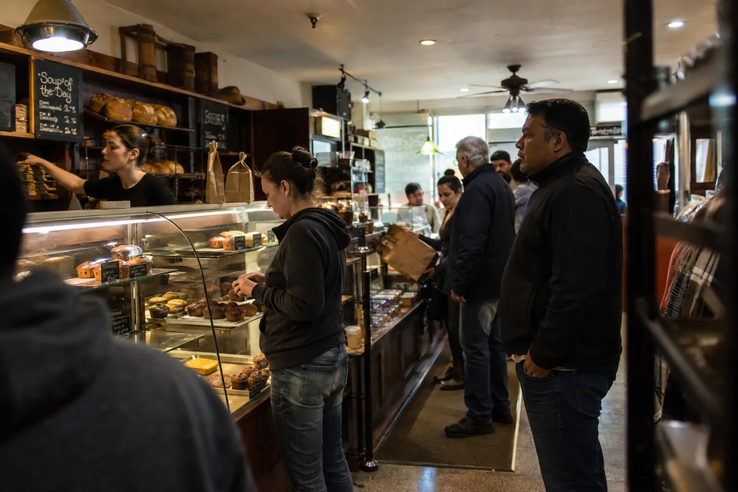 Customers ordering at a bakery counter with a pastry case