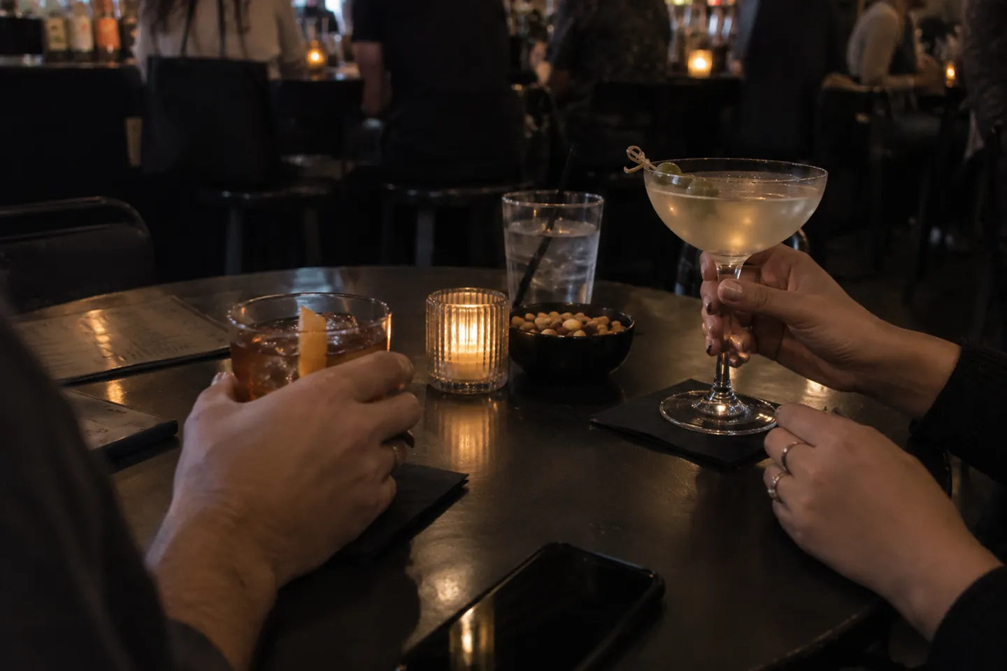 Clientes brindando con cócteles en la mesa de un bar