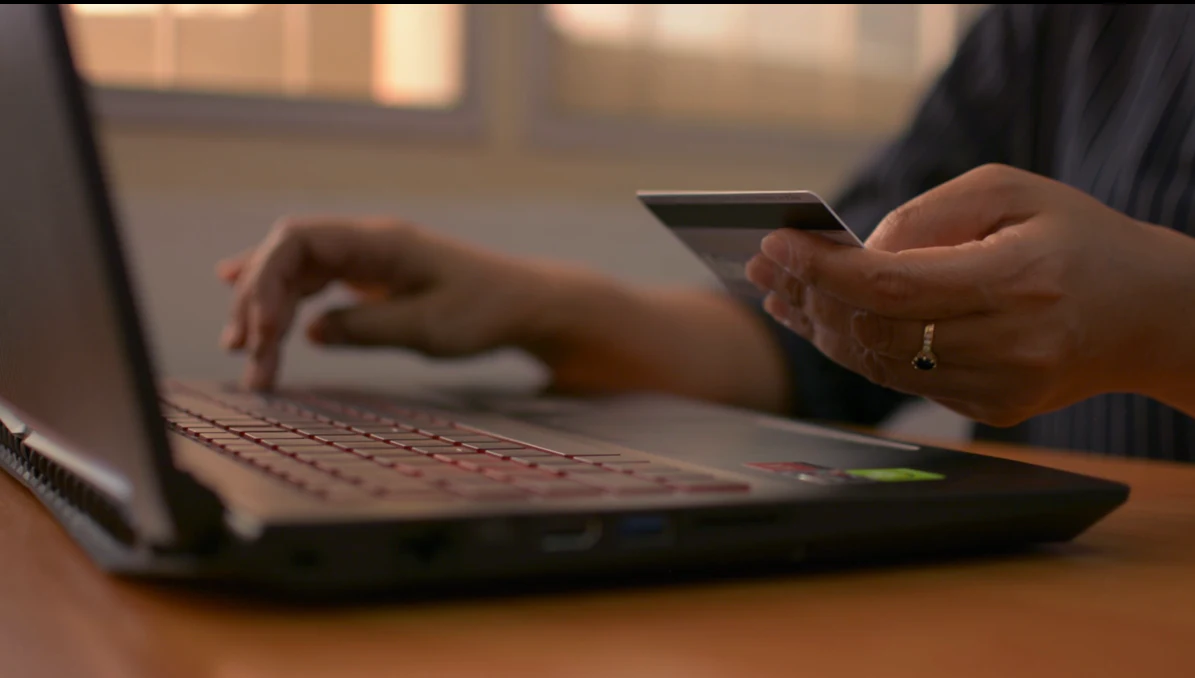 Customer entering an online order while holding a payment card