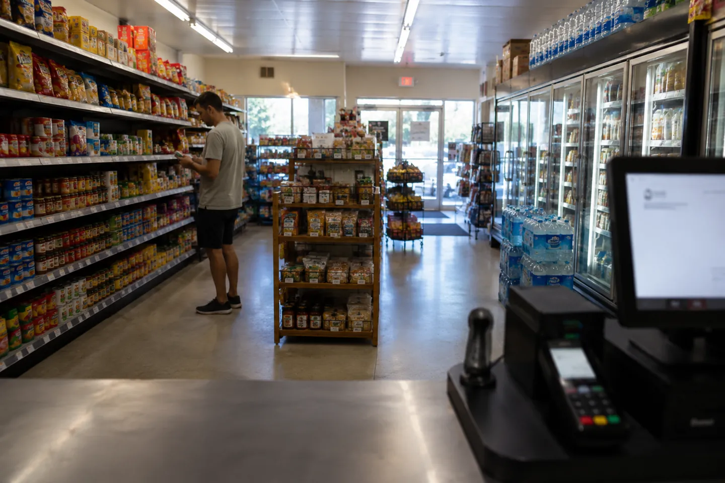 Stocked grocery aisles with a register terminal in the foreground