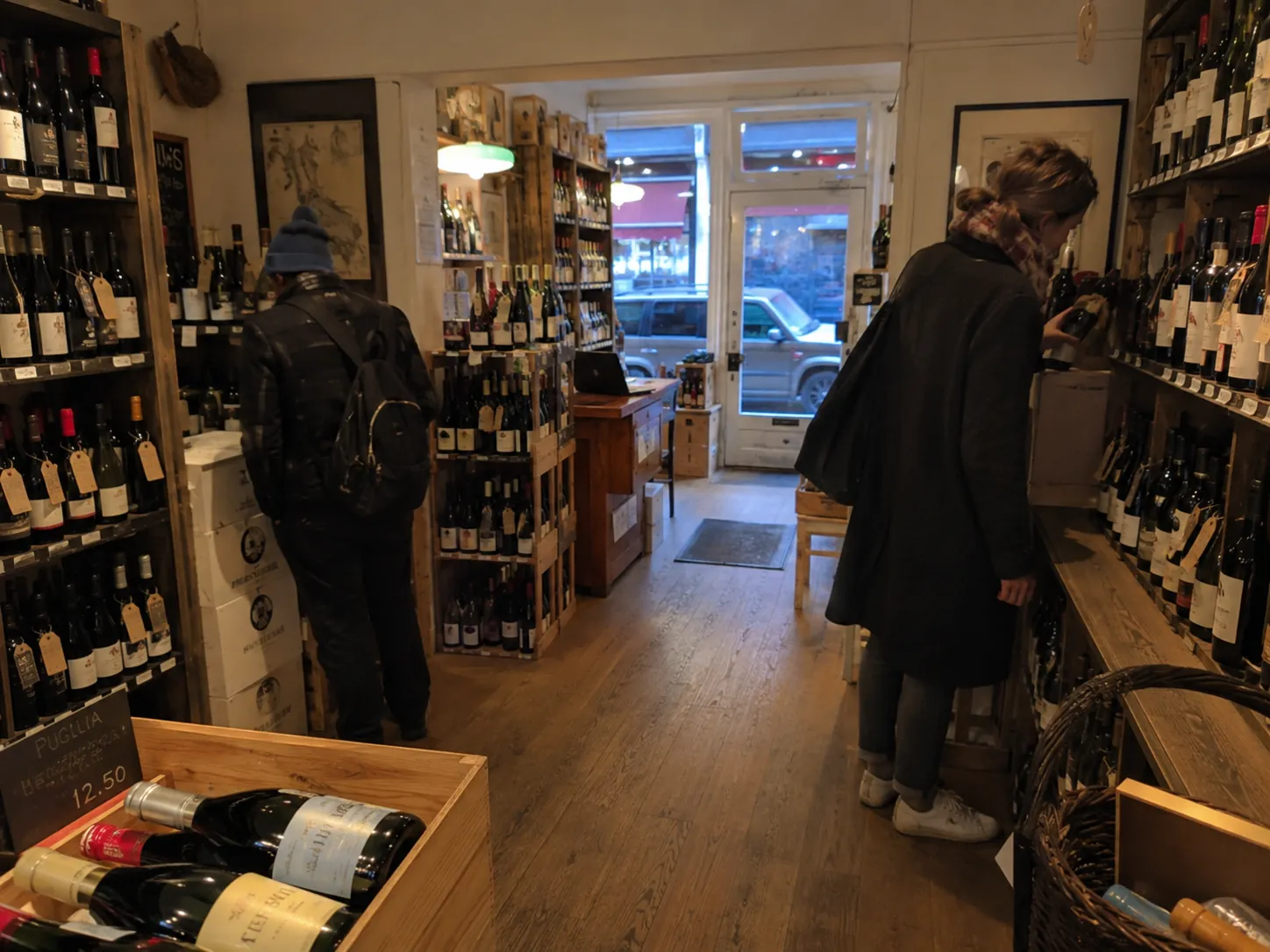 Wine and spirits shop with wooden shelves and customers browsing bottles